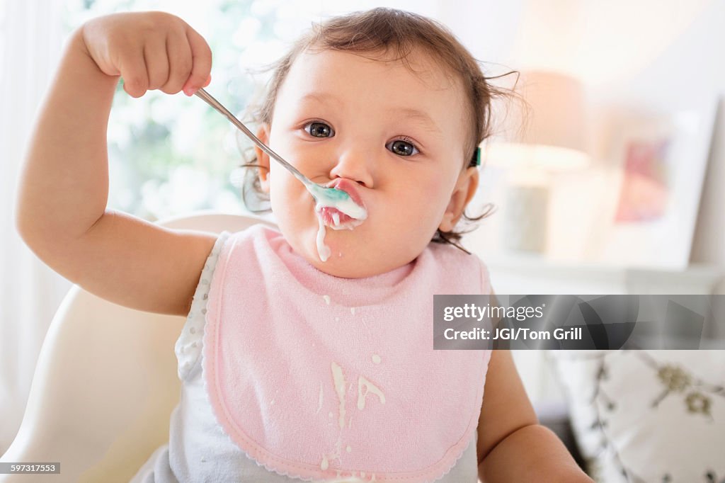 Mixed race baby girl eating yogurt