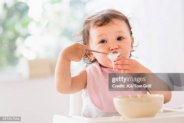 mixed race baby girl eating yogurt - baby eating yogurt stockfoto's en -beelden