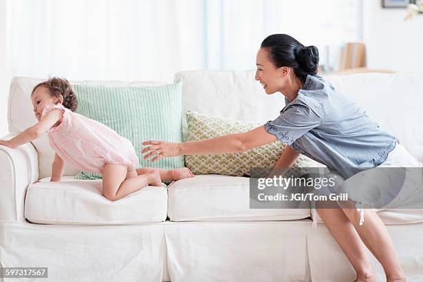 mother and baby daughter playing on sofa - chasing baby stock pictures, royalty-free photos & images