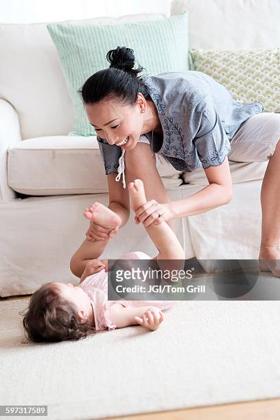 mother and baby daughter playing in living room - tickling feet stock pictures, royalty-free photos & images