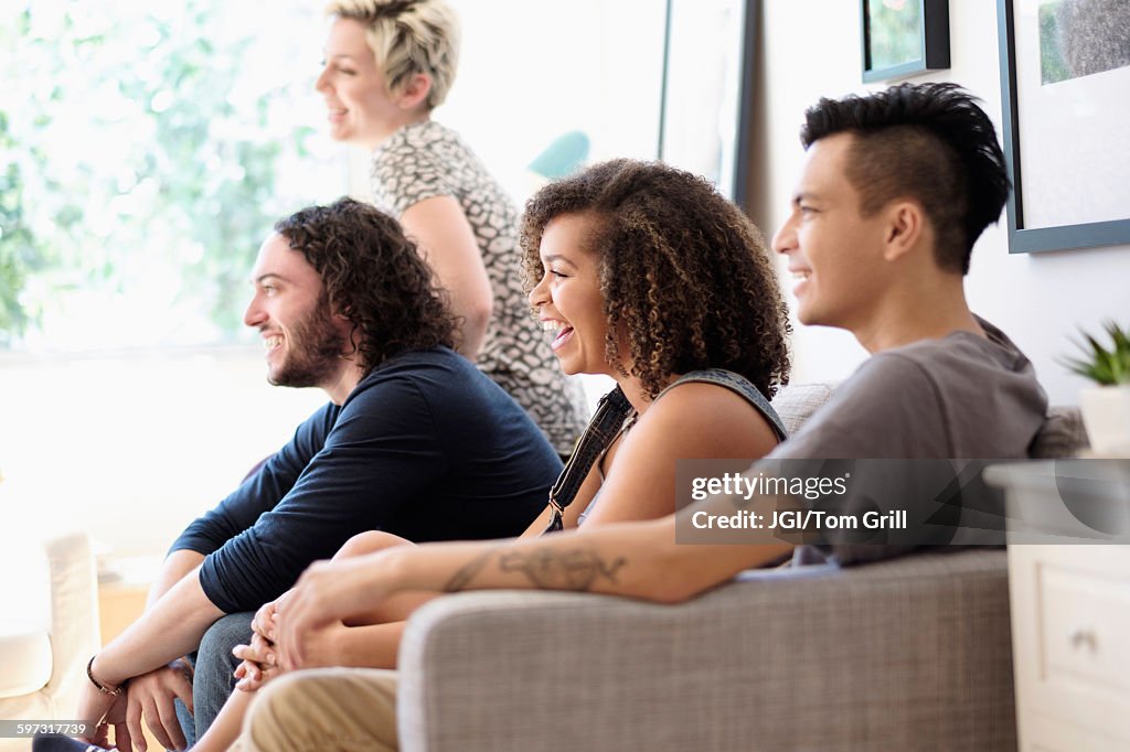 Friends watching television on sofa