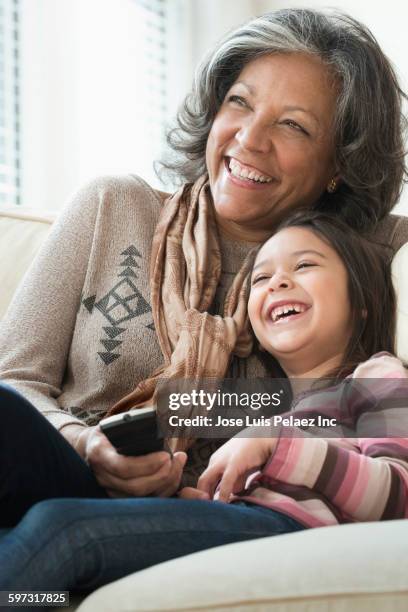 grandmother and granddaughter watching television on sofa - family vertical stock pictures, royalty-free photos & images