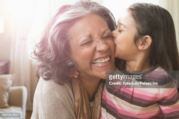 granddaughter kissing cheek of grandmother - granddaughter stock pictures, royalty-free photos & images