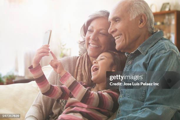 grandparents and granddaughter taking selfie on sofa - grandparent phone stock pictures, royalty-free photos & images