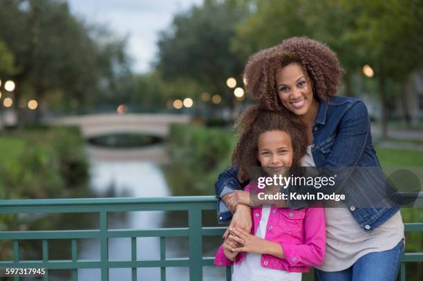 mixed race mother and daughter hugging on bridge - orlando florida family stock pictures, royalty-free photos & images