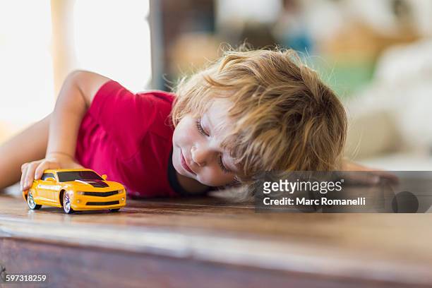 caucasian boy playing with toy car - childrens toys stock-fotos und bilder