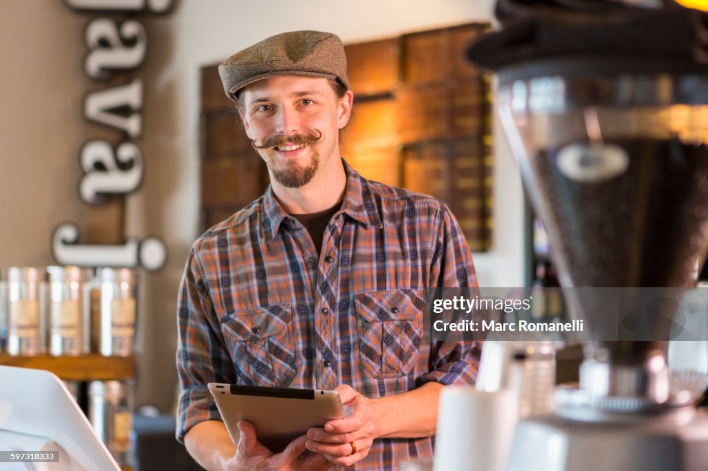 Caucasian barista holding digital tablet in cafe