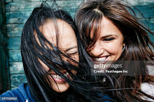 women laughing with hair blowing in wind - asian hair stock-fotos und bilder