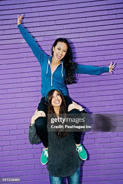 woman carrying friend on shoulders - llevar al hombro fotografías e imágenes de stock