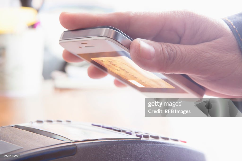 Hispanic woman scanning credit card from cell phone