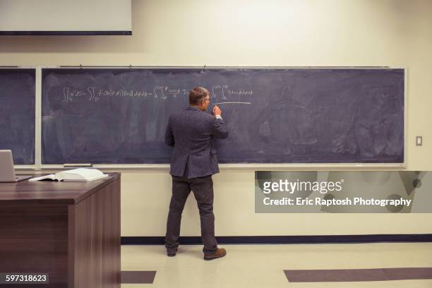 caucasian teacher writing on chalkboard - blackboard stock pictures, royalty-free photos & images