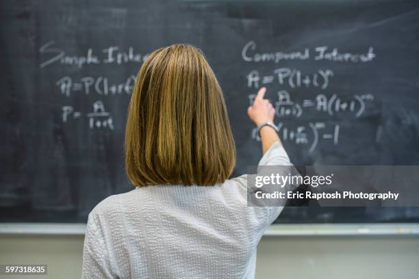 caucasian teacher pointing to chalkboard - teacher board stock pictures, royalty-free photos & images