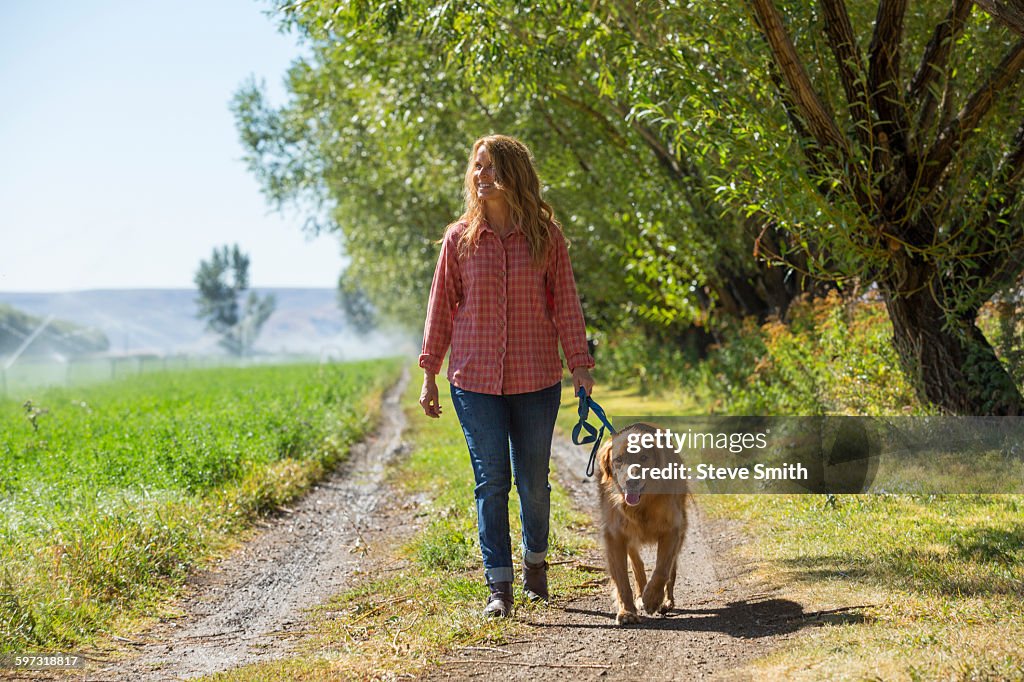 Caucasian woman walking dog on dirt path