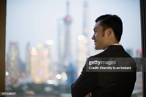 young man looking out of the window smiling. - black hair back stock pictures, royalty-free photos & images