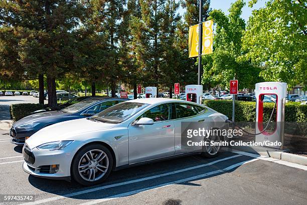 Tesla automobiles plugged in and chargging at a Supercharger rapid battery charging station for the electric vehicle company Tesla Motors, in the...