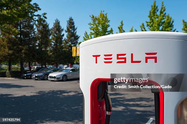 Charger with Tesla logo at a Supercharger rapid battery charging station for the electric vehicle company Tesla Motors, in the Silicon Valley town of...