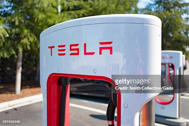 Charger with Tesla logo at a Supercharger rapid battery charging station for the electric vehicle company Tesla Motors, in the Silicon Valley town of...