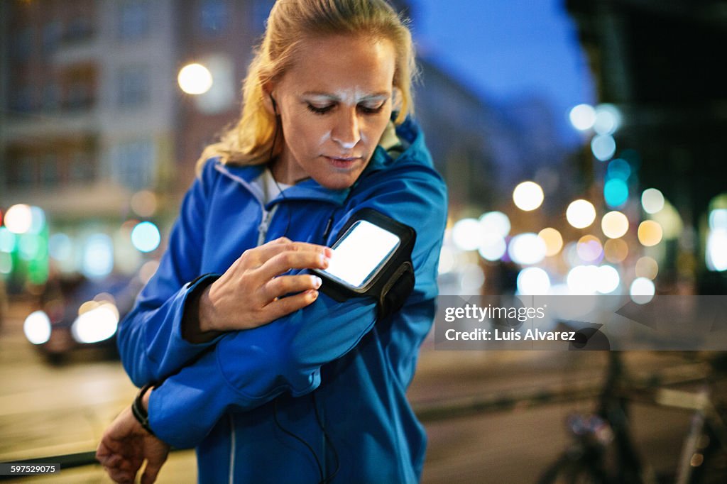 Female runner choosing music on smartphone