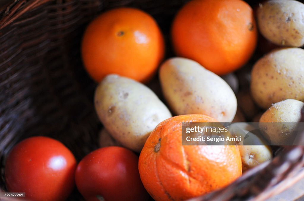 Oranges, potatoes and tomatoes in a basket