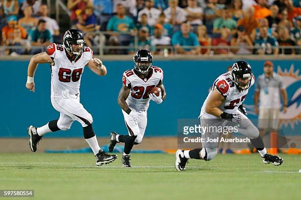 Jacob Tamme and Mike Person lead Cyrus Gray of the Atlanta Falcons as he runs with the ball against the Miami Dolphins during a preseason game on...