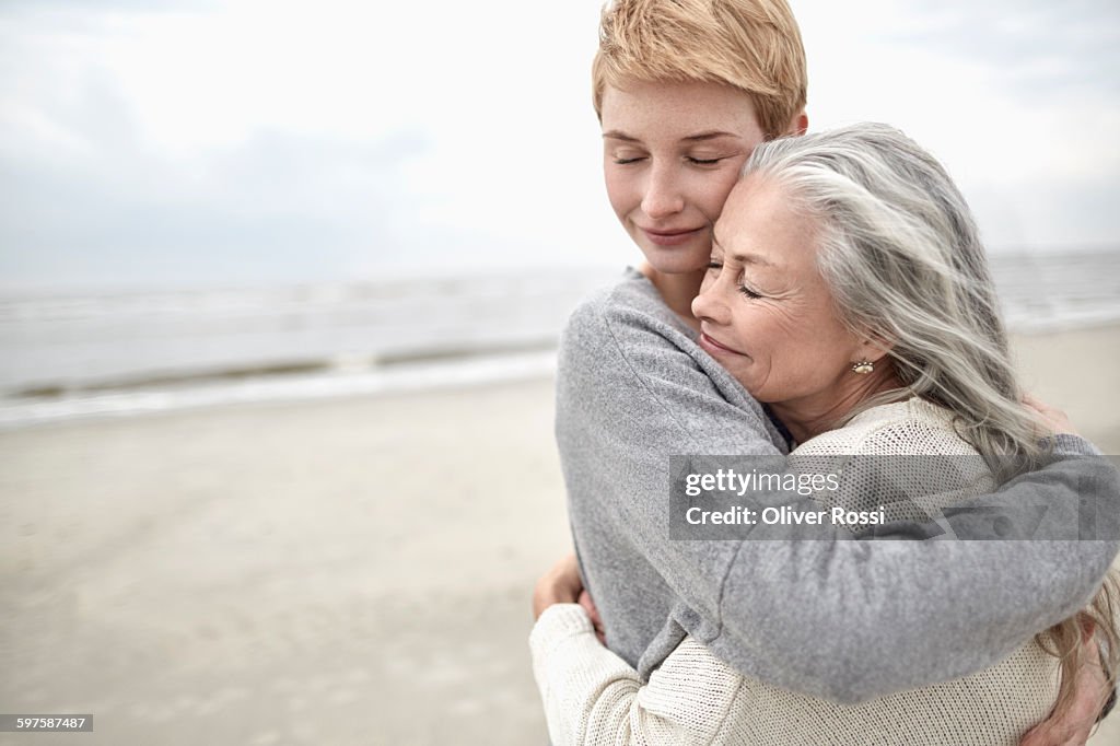 Adult daughter hugging senior mother on the beach