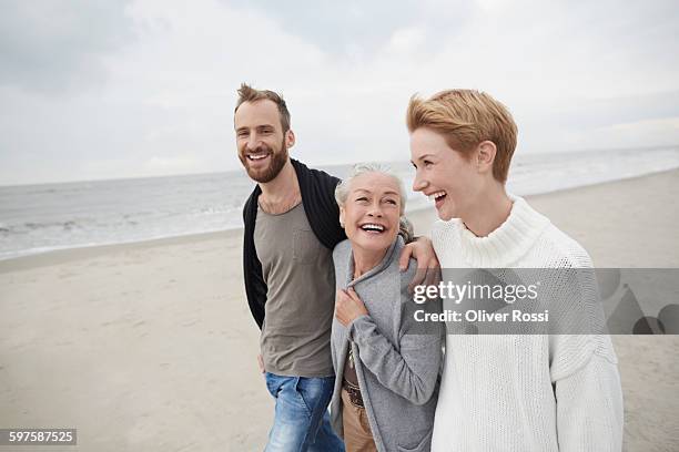 happy couple with senior mother on the beach - family trip in laws stock pictures, royalty-free photos & images