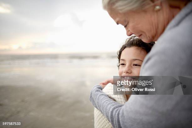 grandmother embracing granddaughter on the beach - granddaughter ストックフォトと画像