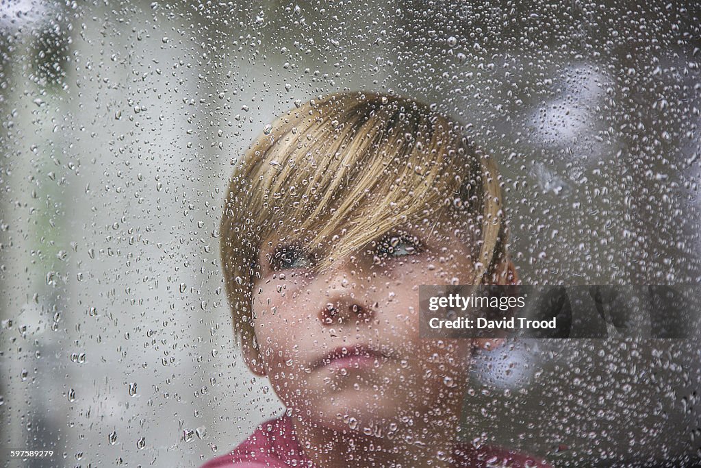 Sad 15 yr old boy looking through window.