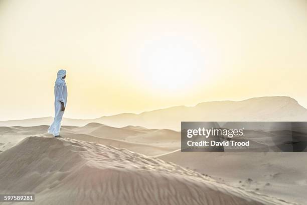 arab man standing in sand dunes near dubai. - dubai sunset desert stock pictures, royalty-free photos & images