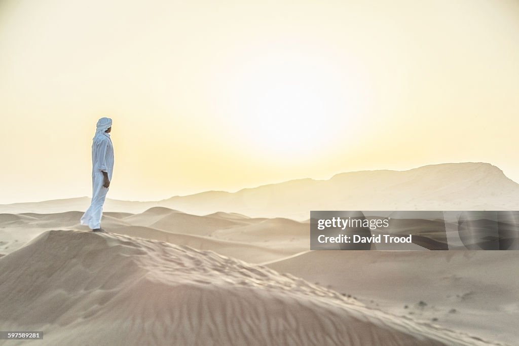 Arab man standing in sand dunes near Dubai.