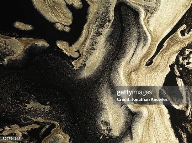 glitter gold paint patterns on black background - or liquide stock pictures, royalty-free photos & images