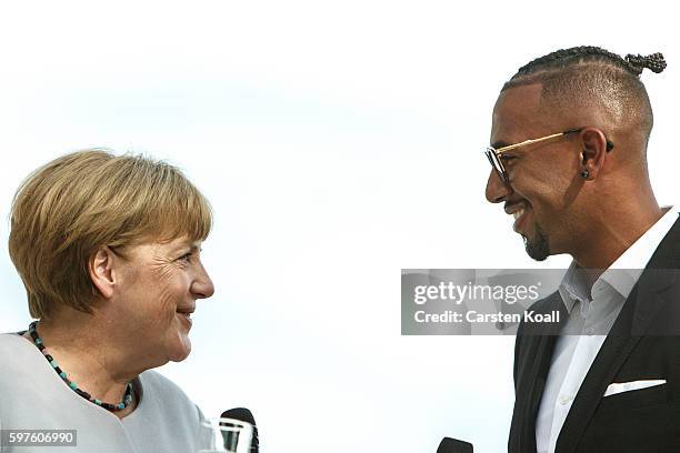 German Chancellor Angela Merkel talks with Jerome Boateng during the annual open-house day at the Chancellery on August 28, 2016 in Berlin, Germany....