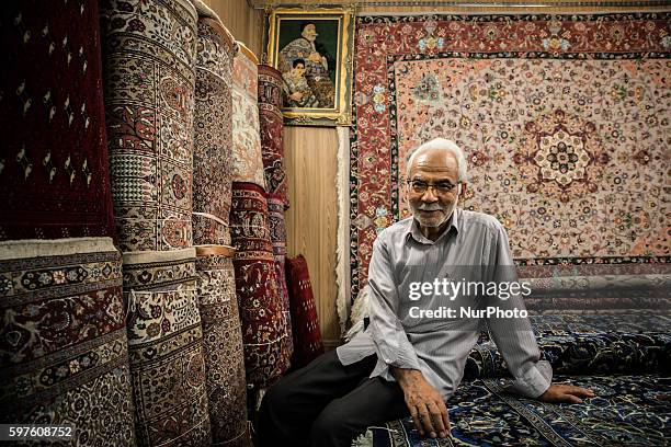 An Iranian carpet vendor poses in his shop at the old bazaar on August 28, 2016 in the city of Mashhad, Iran. Market Iranian carpets in the city of...