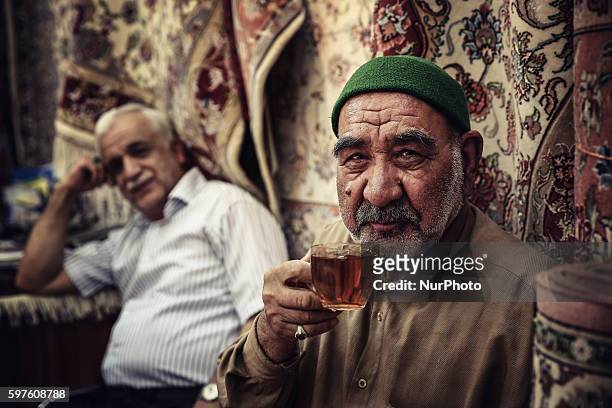 An Iranian carpet vendor poses in his shop at the old bazaar on August 28, 2016 in the city of Mashhad, Iran. Market Iranian carpets in the city of...