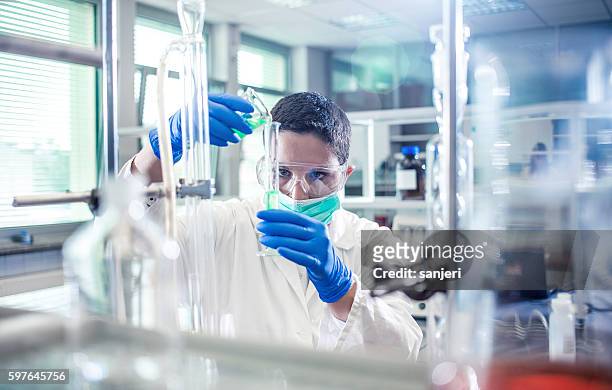 cientista derramando um reagente em um cilindro de medição - reagente - fotografias e filmes do acervo