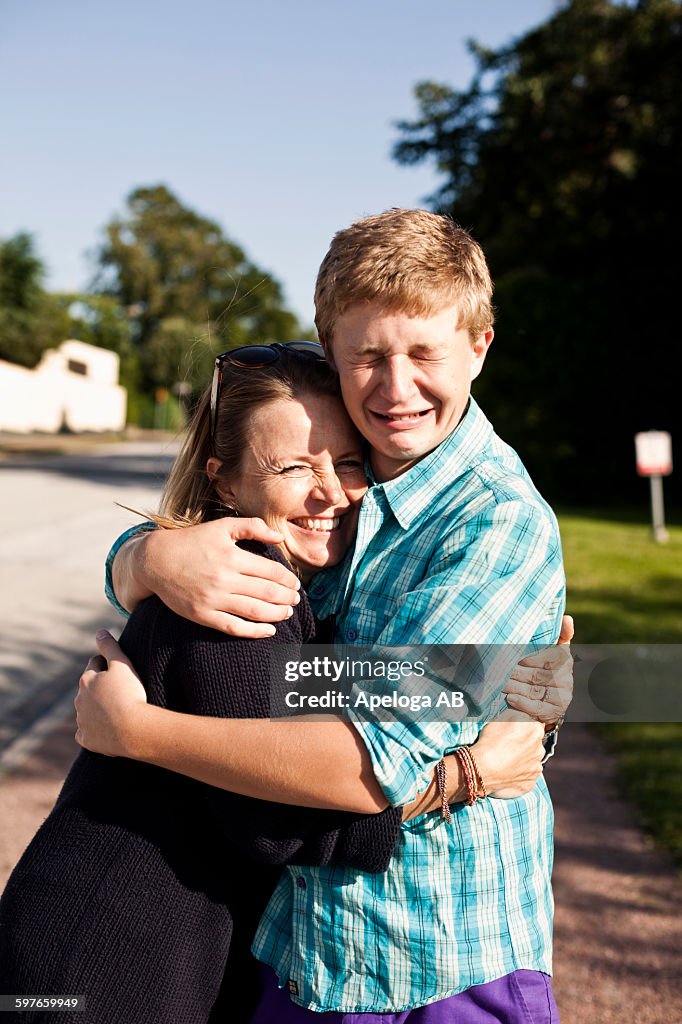 Portrait of happy woman embracing crying son