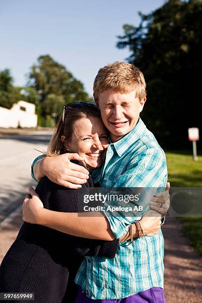 portrait of happy woman embracing crying son - teardrop stock pictures, royalty-free photos & images