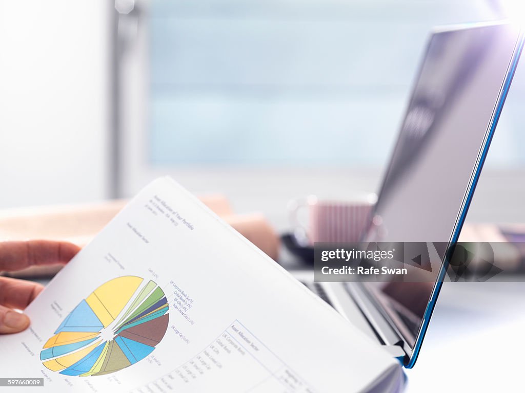 Man reviewing financial affairs using investment statement and laptop