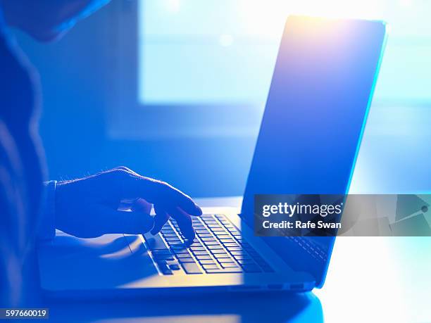 man typing at laptop computer - stalking photos et images de collection