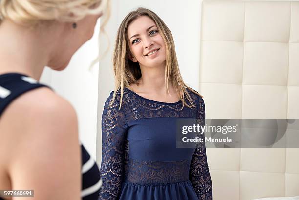 young woman wearing blue lace dress looking at friend smiling - lace dress stock pictures, royalty-free photos & images