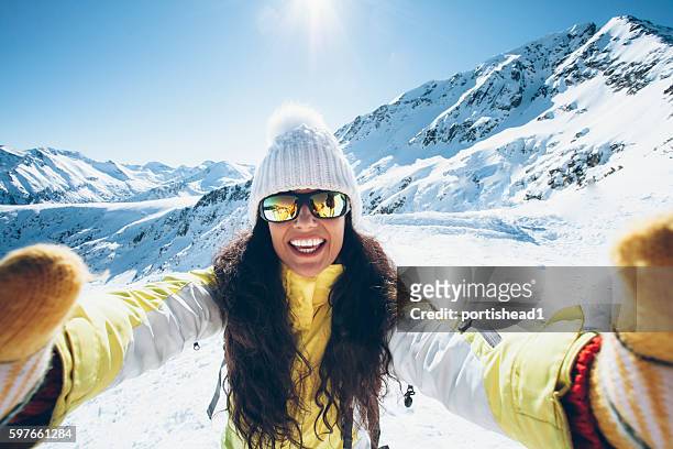 lächelnde junge frau mit spaß im schneeberg - wintersport stock-fotos und bilder