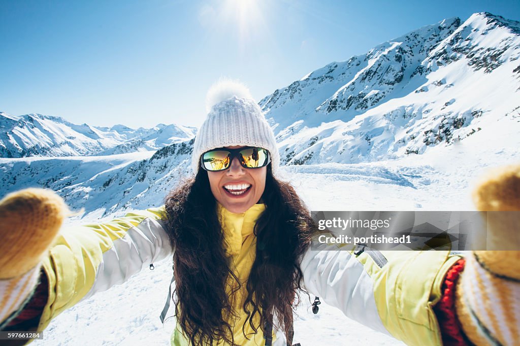 Smiling young woman having fun in the snow mountain