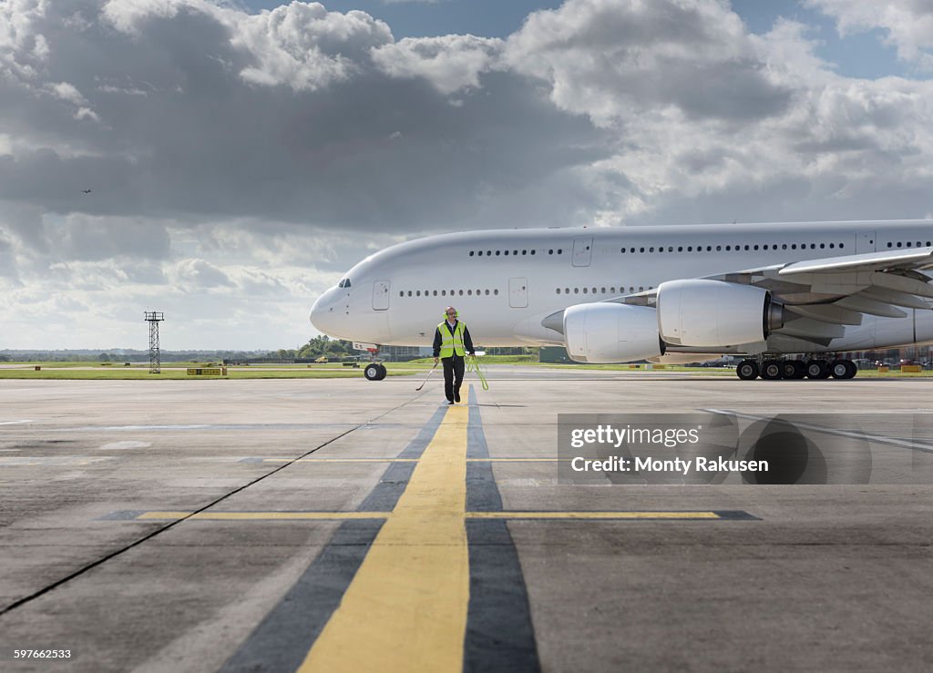 Chief engineer walking from runway as A380 aircraft departs from airport