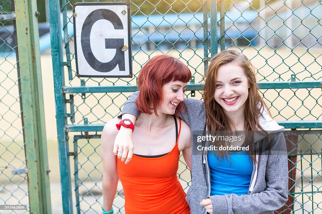 Young women standing beside sports ground, London, UK