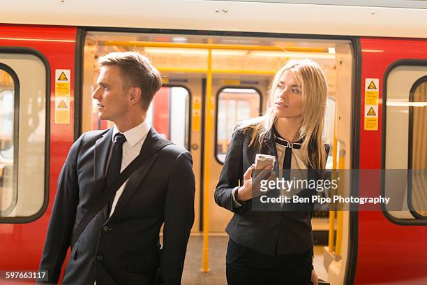 businessman and businesswoman alighting train, london underground, uk - aussteigen stock-fotos und bilder