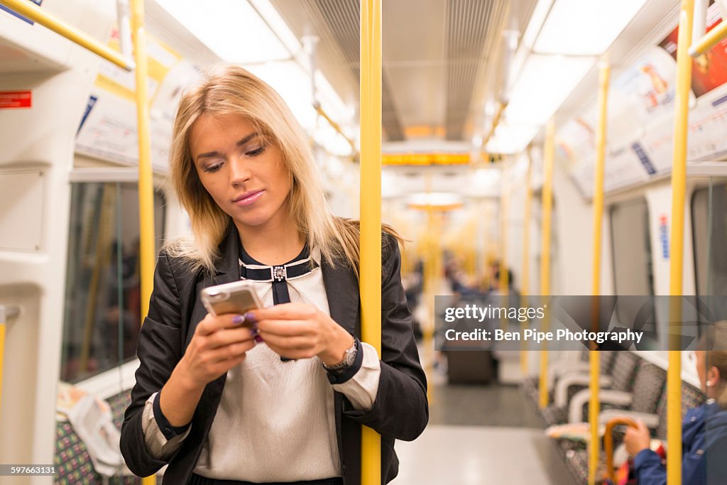 Businesswoman texting on tube, London Underground, UK