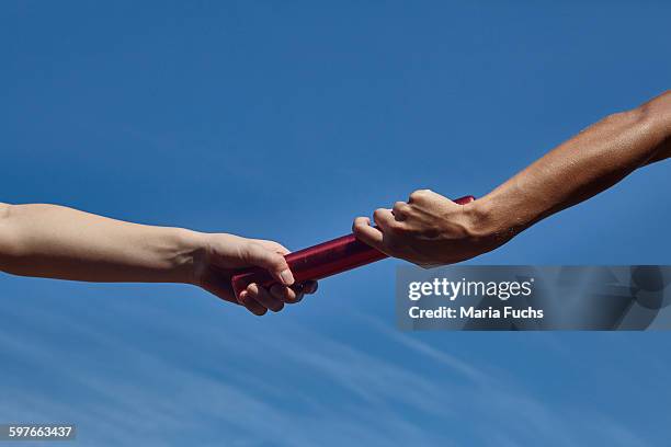 hands of female relay runners passing baton against blue sky - stafett bildbanksfoton och bilder