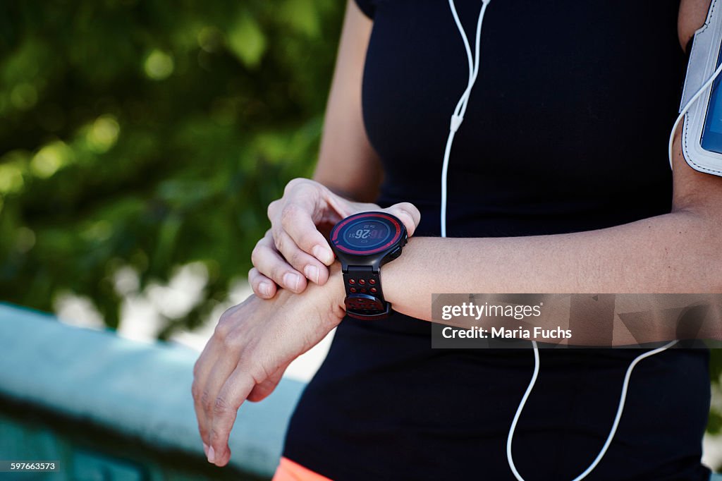 Cropped shot of young female runner setting smartwatch