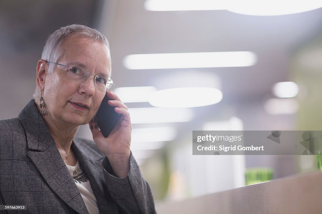 Senior businesswoman chatting on smartphone in hotel lobby