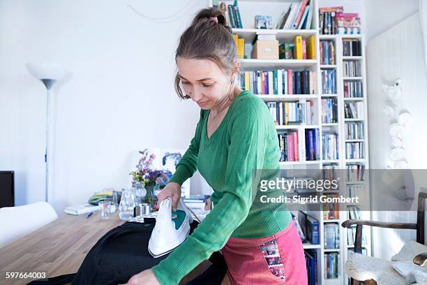 side view of mid adult woman ironing, looking down - つまらない仕事 ストックフォトと画像